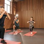 Adults practicing exercises on yoga mats in a contemporary studio setting.